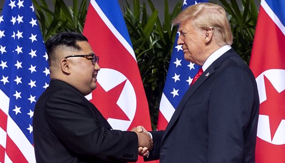 Kim Jong Un and Donald Trump shake hands in front of their flags
