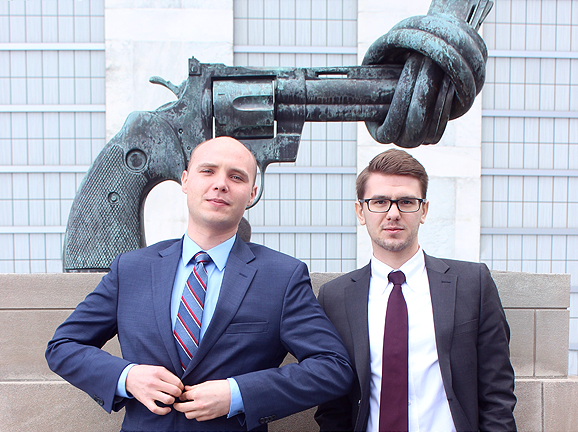 Interns outside in front of statue of gun with a knot at the end. 