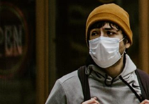 Teen boy wearing a paper surgical mask, looking frightened