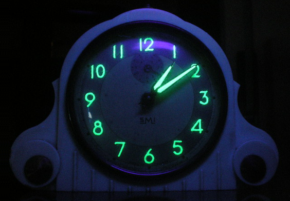 Clock numbers and hands glow green in the dark