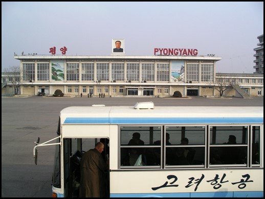 A bus transporting arrived passengers with airport building at the back