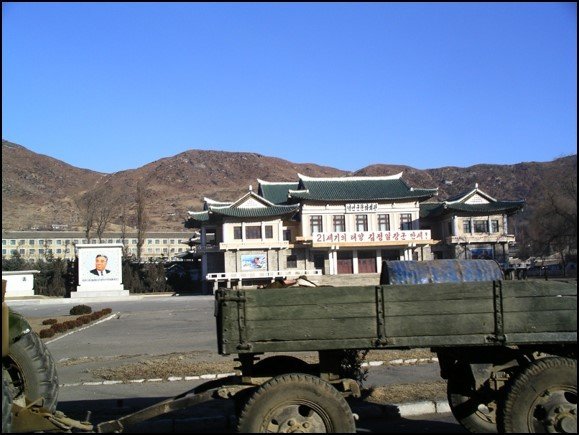 A rustic truck in the foreground, traditional Korean architecture building, and mountains in the back on a day with a blue sky