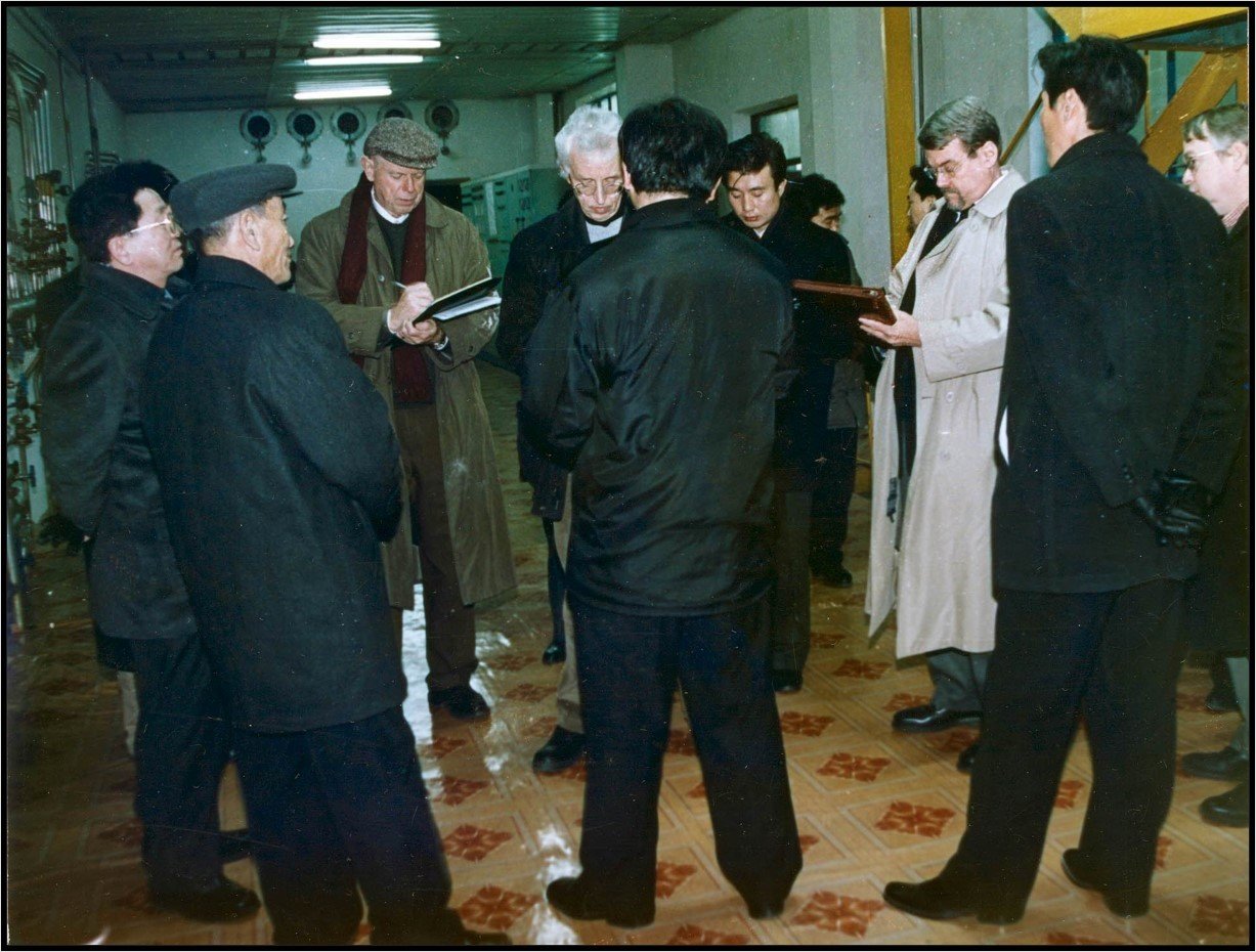 Group of men in a hallway standing in circle; Americans taking notes