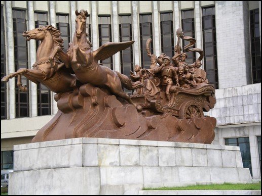 A sculpture of winged horses in front of an entrance to a public building