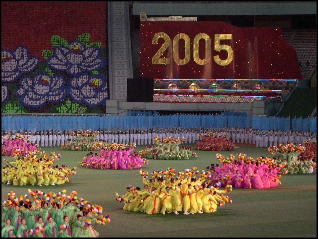 Thousands of brightly dressed dancers performing a complex mass choreography
