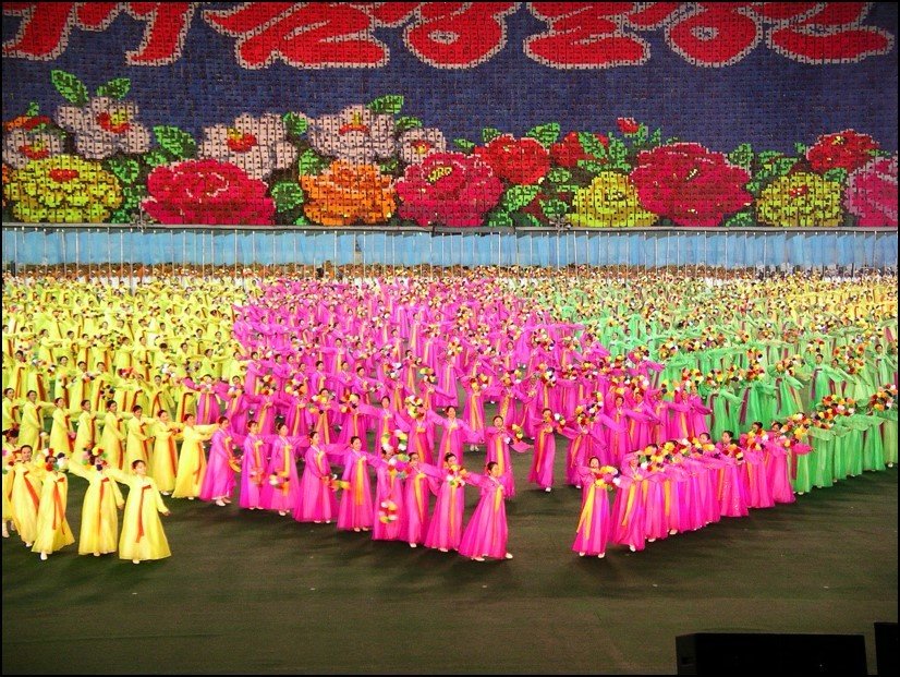 Thousands of brightly dressed dancers performing a complex mass choreography