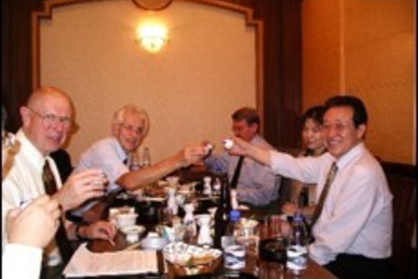 Group photo of people at a table toasting.