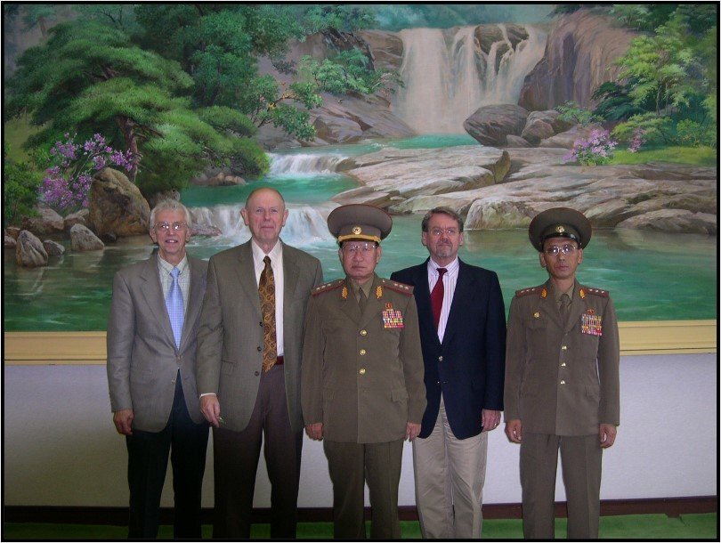 Two North Korean military officers with three Americans in front of a landscape painting