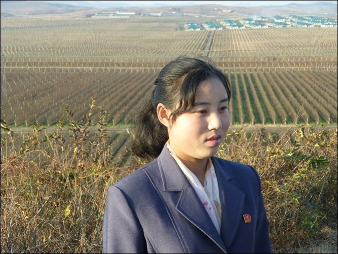 Young Korean woman in formal attire with a vast agricultural field behind her