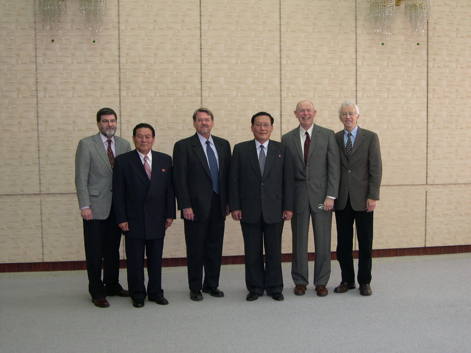 Six men in business suits posing for picture.