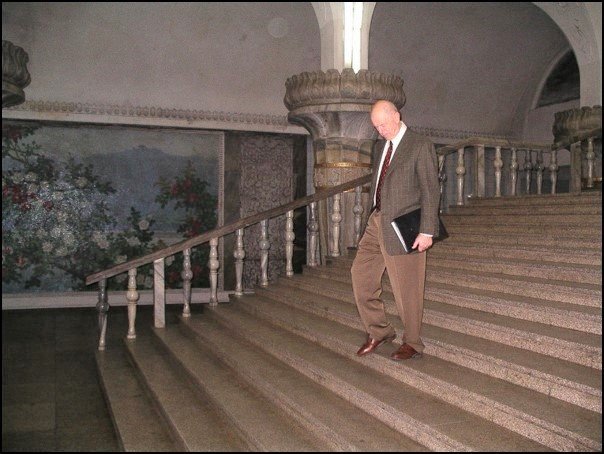 Man walking down stairs into a marble-walled subway station