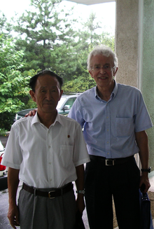 Two men, Hecker and DPRK host, posing for photo