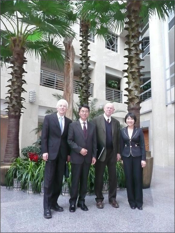 Three men and a woman in business attire posing in a courtyard