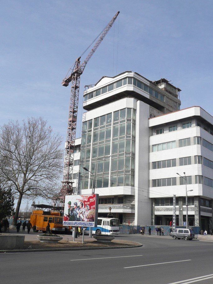 A tall modernist building with a construction crane at its side