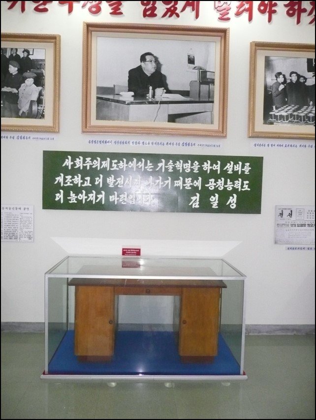 Photos on the wall, signs in Korean language, and a desk as part of display to mark the prior visits of two country leaders
