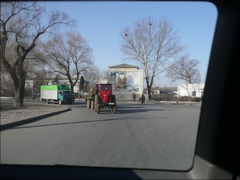 A tractor with a loaded trolley and a truck on a country road