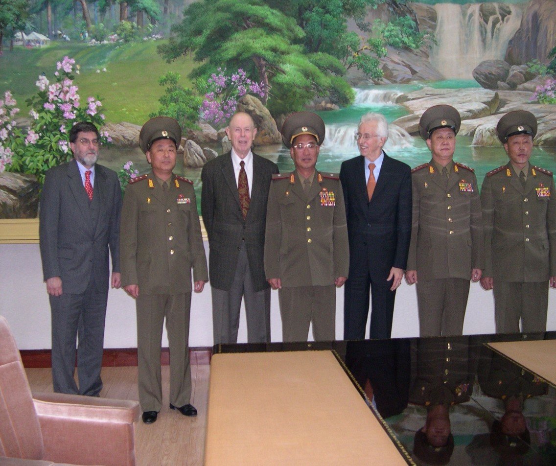 Four North Korean military officers in formal attire posing for photo with three American guests.