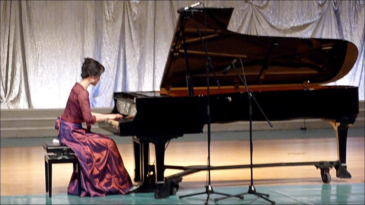 A woman in concert dress playing the concert piano forte