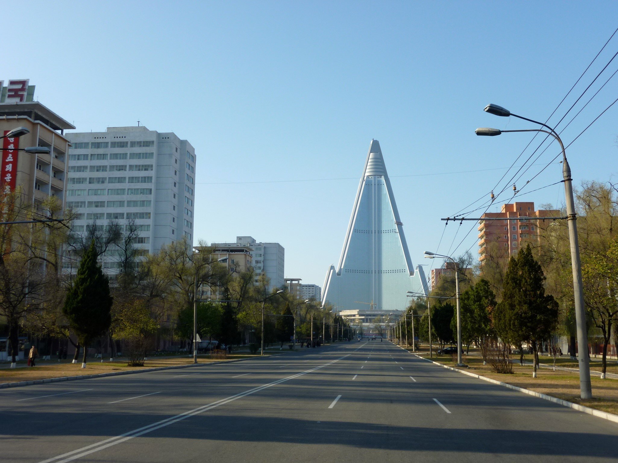 Pyramid shaped building in front of an empty three lane street. 