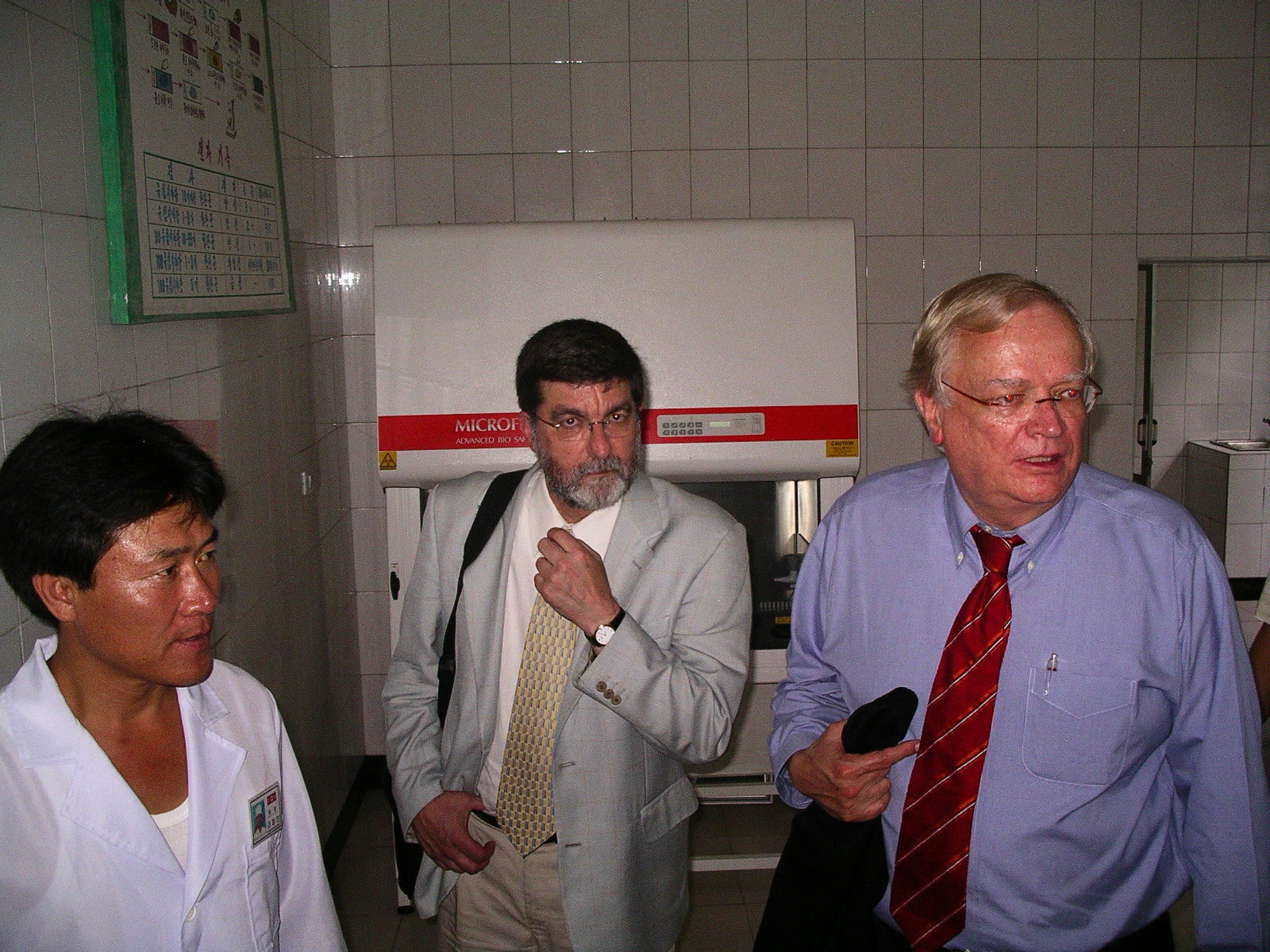 Two Americans and North Korean man in white doctor gown in a hospital hallway