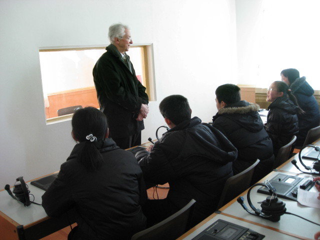 Man standing in front of a class with everyone wearing warm clothes inside