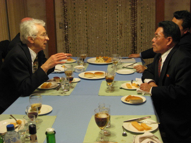 Two men in earnest conversation across a laid dinner table
