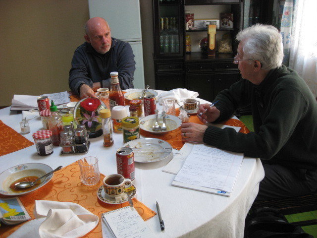 Two men talking at a lunch table laid with tableware and condiments