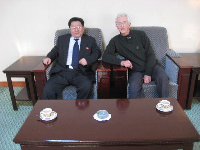 Two men sitting in low armchairs next to each other and looking in the camera