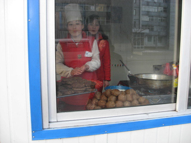 Uniformed street food vendor inside her booth