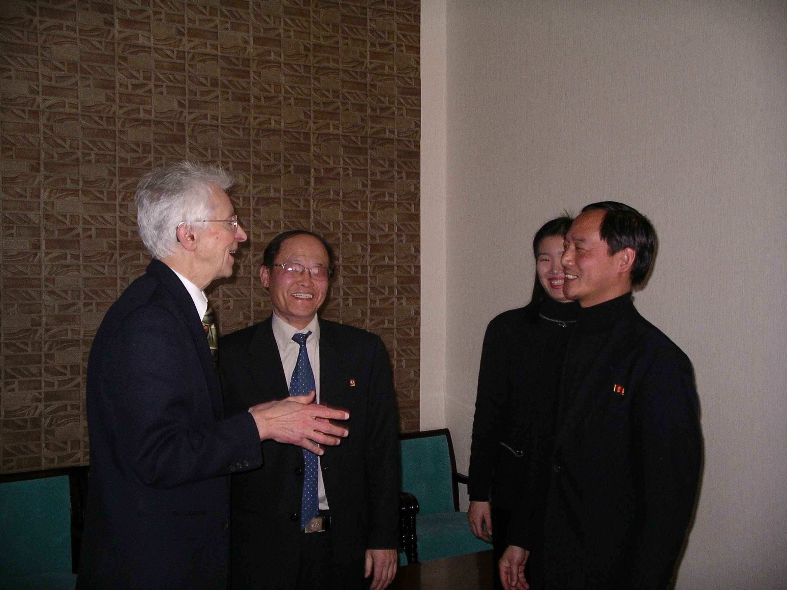 Hecker in lively conversation with Korean officials facing each other in a small circle