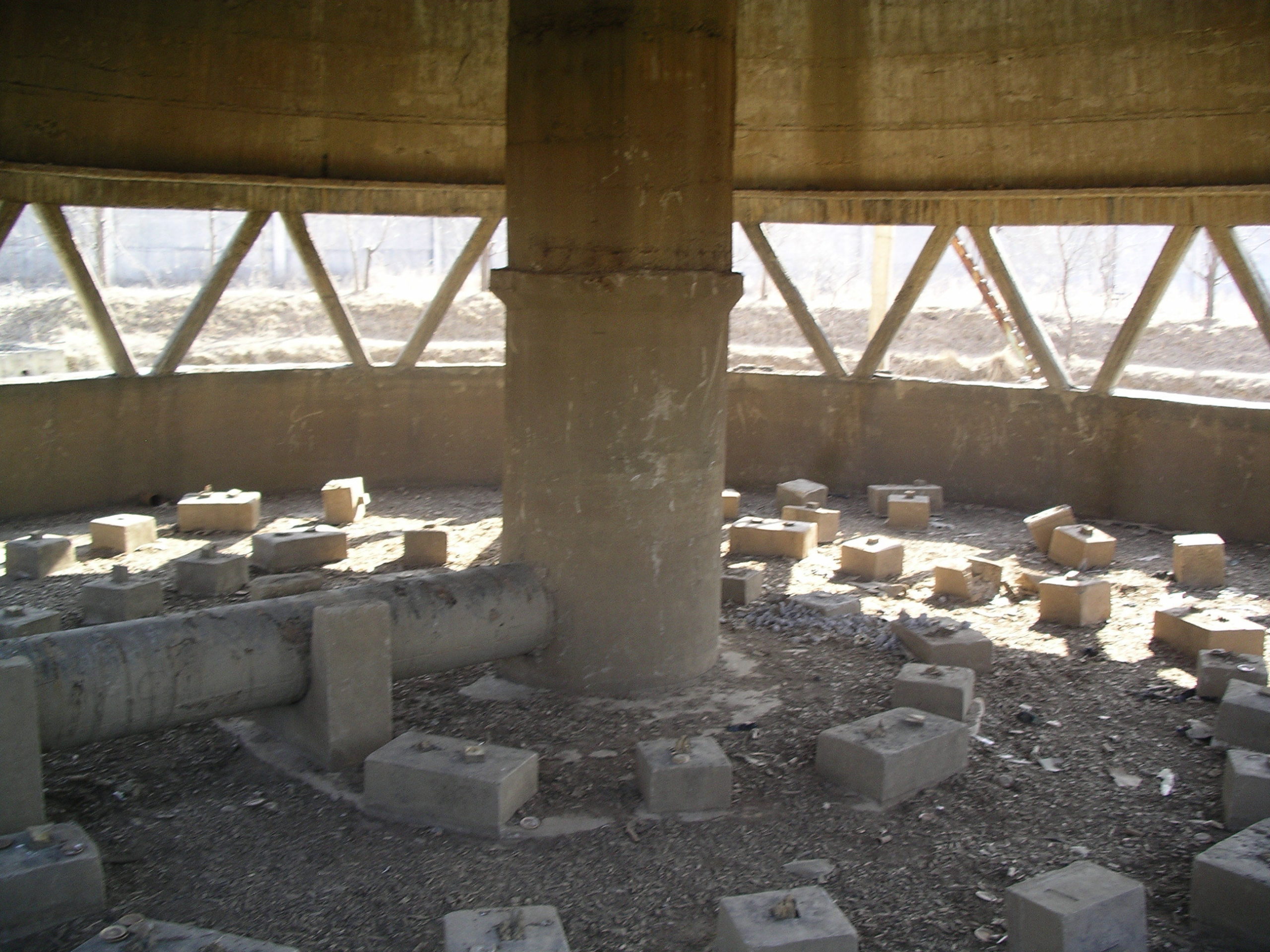 An open foundation of the cooling tower with concrete blocks strewn around in concentric pattern and other pieces of removed piping