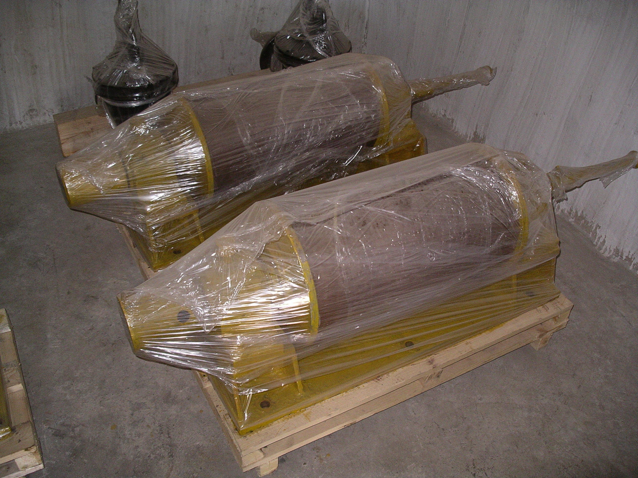 Motors painted mustard color wrapped in transparent plastic stored on wooden pallets