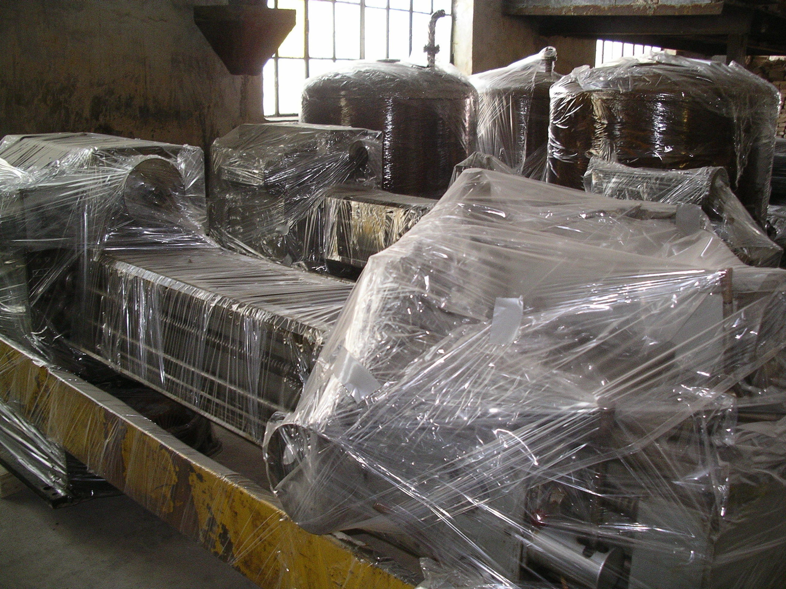 Massive metal equipment wrapped in clear plastic for storage