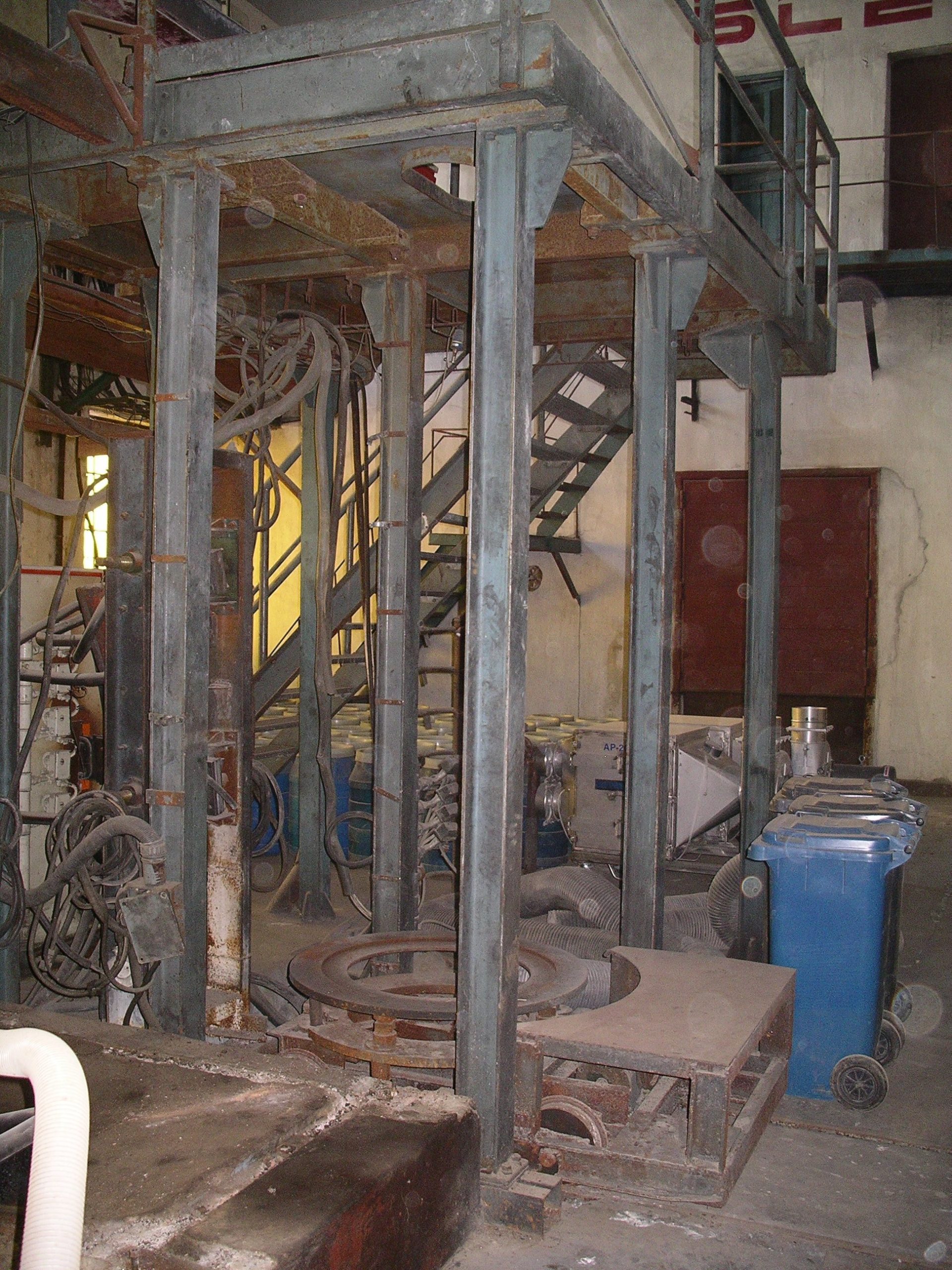 Five or more upright steel columns with metal stairs leading upward in the back and some tangled hoses and wires