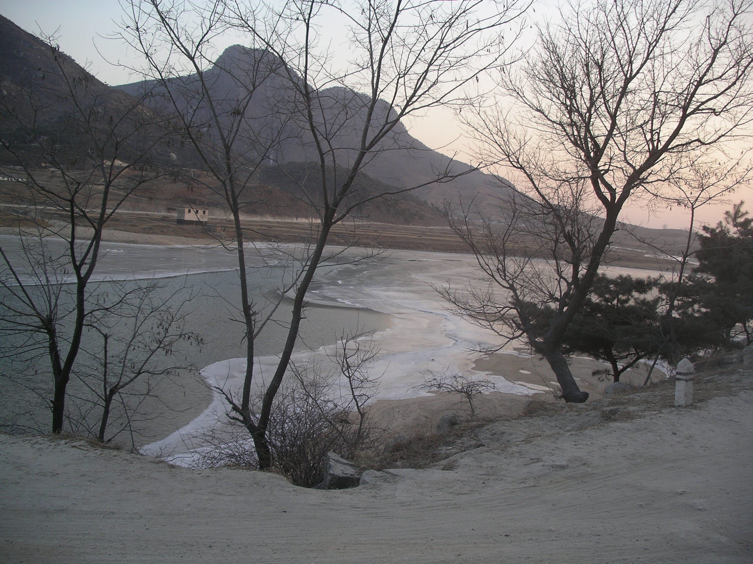 A dirt bank and a river with curved river bed with hills in the back