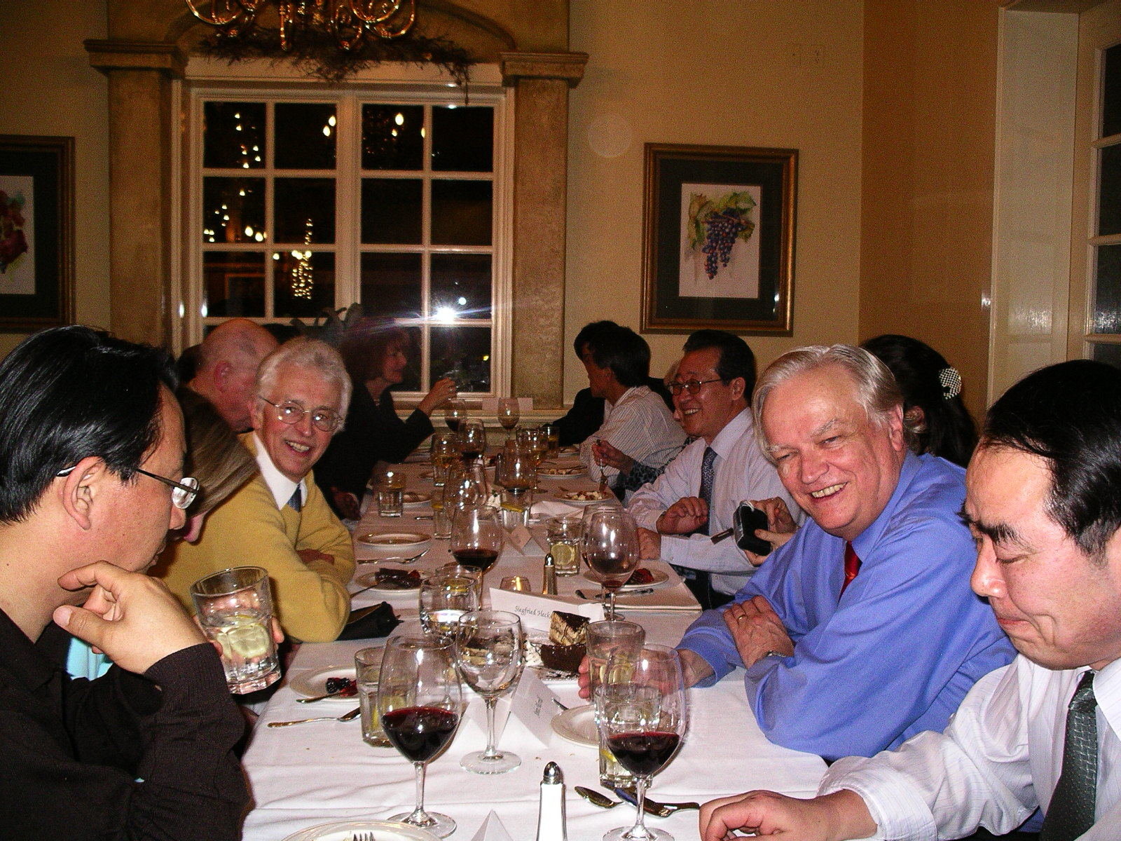 Company of smiling relaxed people with wine glasses at a restaurant table