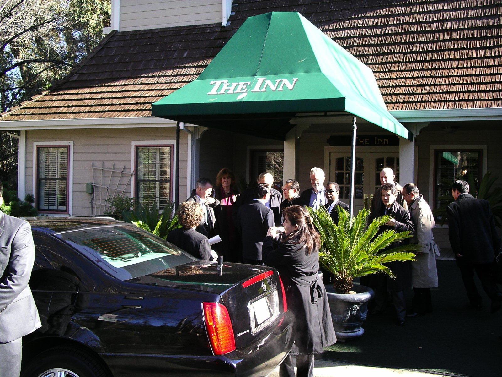 People crowding in the inn entryway with a black vehicle parked by Kim Gye Gwan delegation arrives in Saratoga for meeting with Stanford University group.