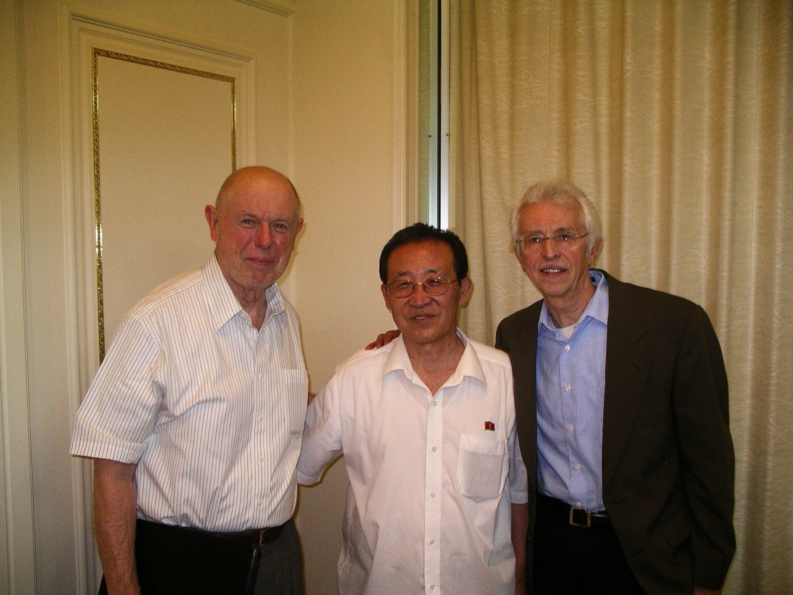 North Korean official flanked by two American men (Lewis and Hecker) posing for a photo