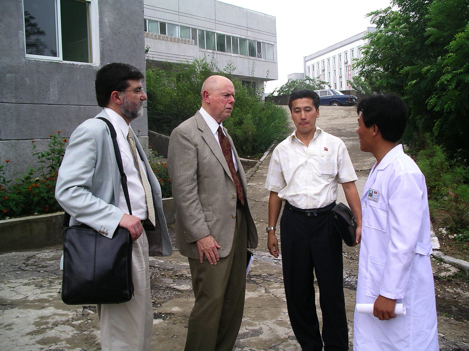 Four men talking outside a gray concrete building