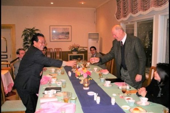 The two men shaking hands over dinner table