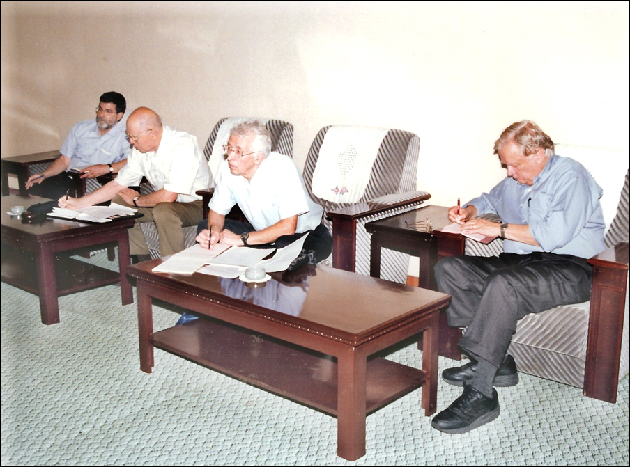 Four men sitting in low chairs taking notes