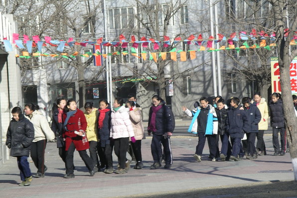 Large group of young people walk in pairs along the street decorated with pennant banners