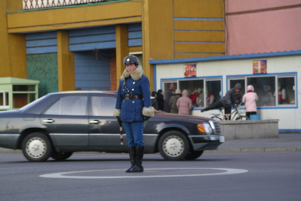 Young woman in warm winter uniform with a conductor stick in hand directing street traffic