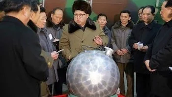 North Korean leader and officials around a round bomb that looks like a disco ball