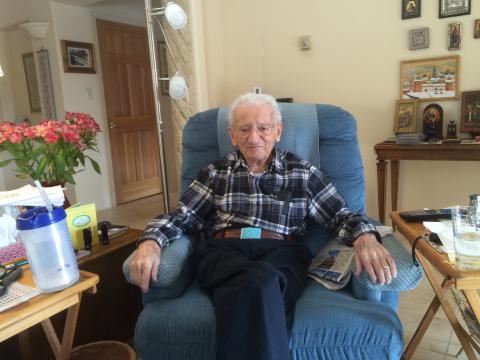 Man sitting in a blue chair in a living room.