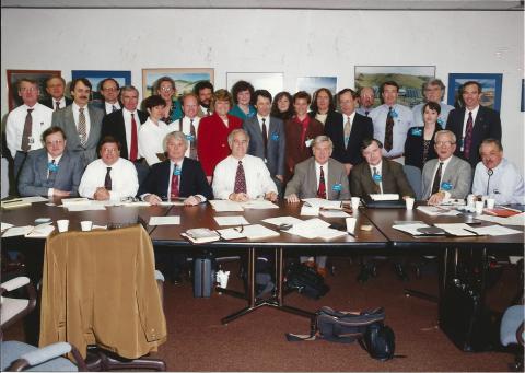 Group photo of people at and behind conference tables