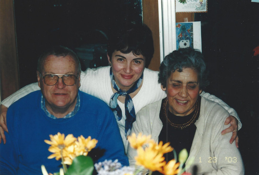 Three people smiling for the camera near a table with yellow flowers.