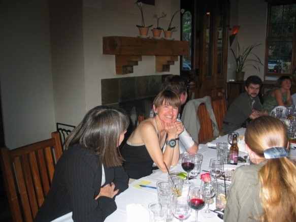 People sitting a table with one woman looking at the camera, smiling.