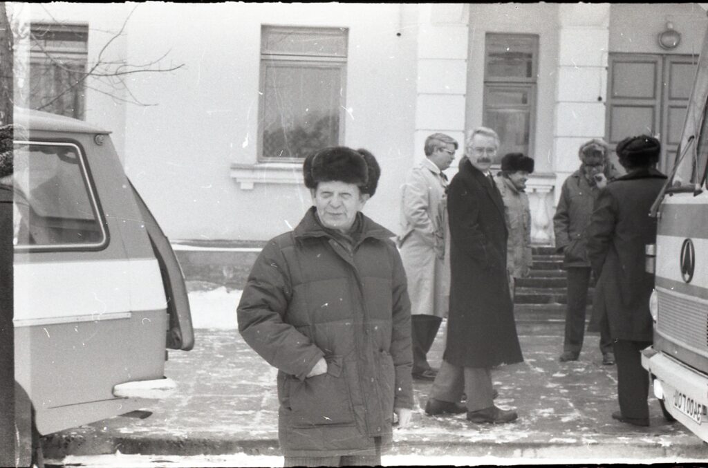 Man standing for the camera outside in a hat and coat