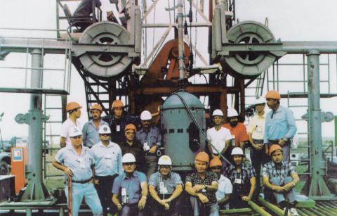Workers wearing hard hats in front of large machinery.
